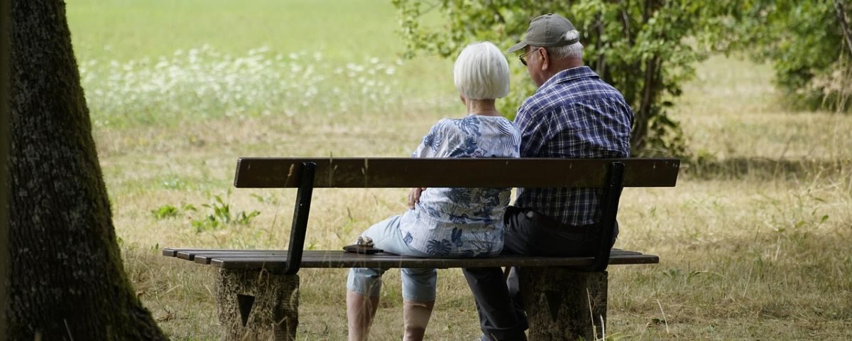 Older couple setting on bench at park